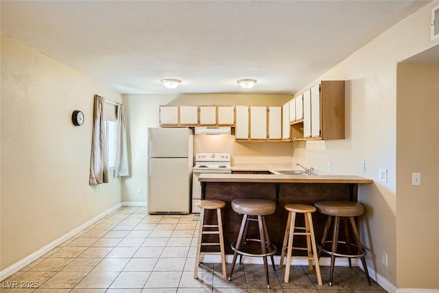 kitchen with kitchen peninsula, sink, white appliances, a breakfast bar area, and light tile patterned floors