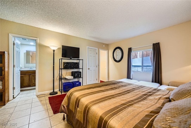 bedroom featuring light tile patterned flooring, ensuite bathroom, and a textured ceiling