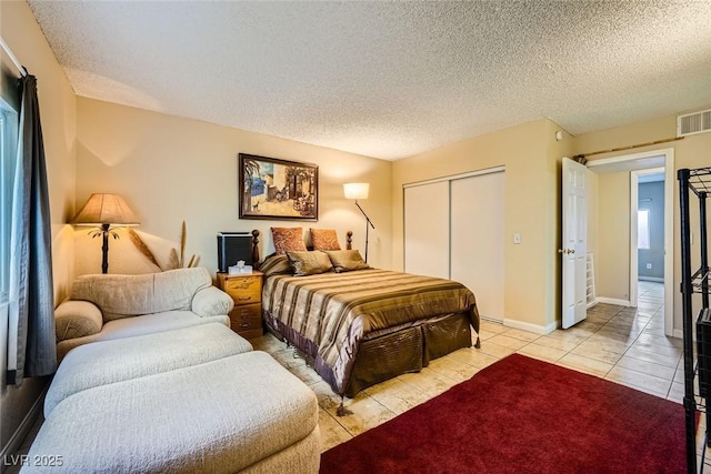 bedroom with a textured ceiling, a closet, and light tile patterned floors