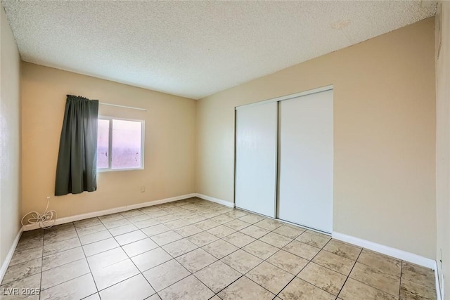 unfurnished bedroom featuring a textured ceiling, a closet, and light tile patterned floors