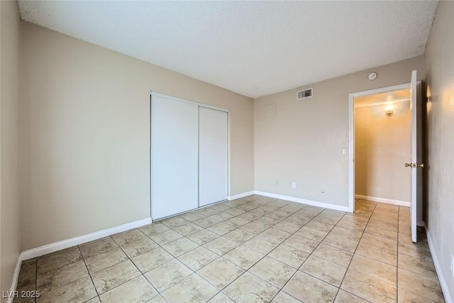 unfurnished bedroom featuring light tile patterned floors, a closet, and a textured ceiling