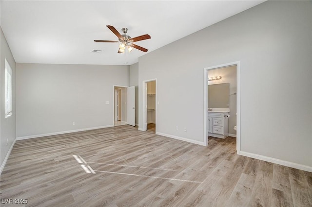 unfurnished bedroom featuring a spacious closet, ceiling fan, light hardwood / wood-style flooring, a closet, and ensuite bath