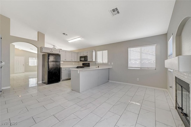 kitchen with black appliances, vaulted ceiling, and kitchen peninsula