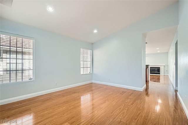 unfurnished room featuring light hardwood / wood-style floors and a brick fireplace