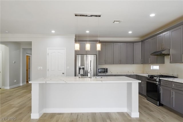 kitchen featuring visible vents, under cabinet range hood, light stone counters, appliances with stainless steel finishes, and a kitchen island with sink