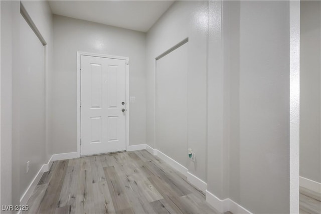 doorway to outside featuring baseboards and light wood finished floors