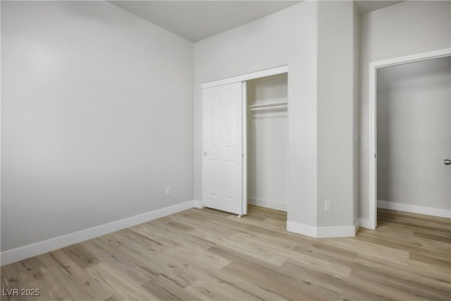 unfurnished bedroom with light wood-style flooring, baseboards, and a closet