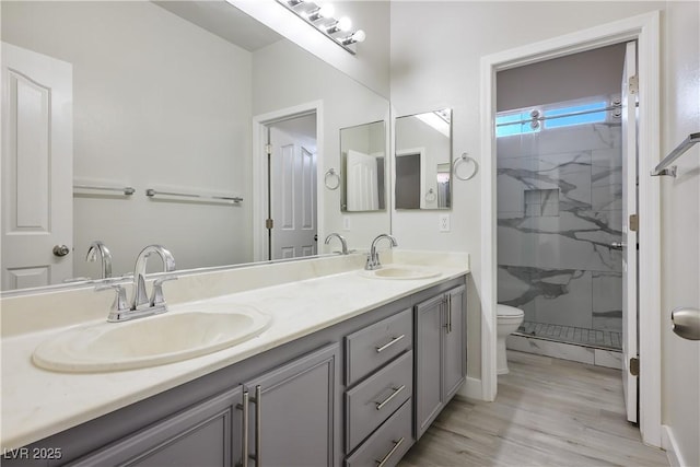 bathroom with hardwood / wood-style flooring, toilet, vanity, and tiled shower