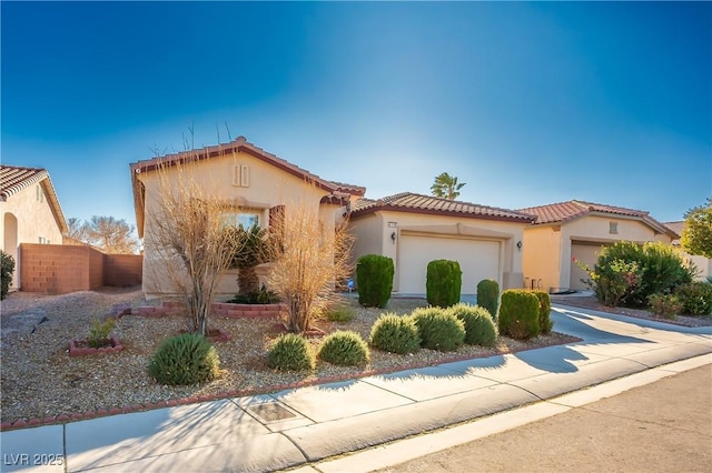 mediterranean / spanish-style home featuring fence, driveway, stucco siding, a garage, and a tiled roof