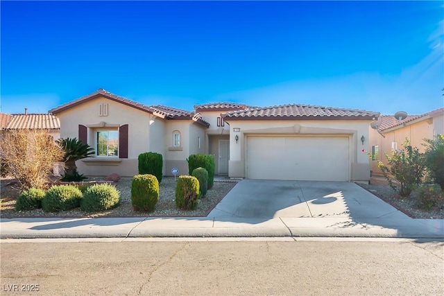 mediterranean / spanish-style home featuring a tile roof, stucco siding, an attached garage, and concrete driveway