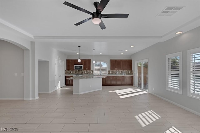 kitchen featuring ceiling fan, a center island, hanging light fixtures, decorative backsplash, and light tile patterned floors