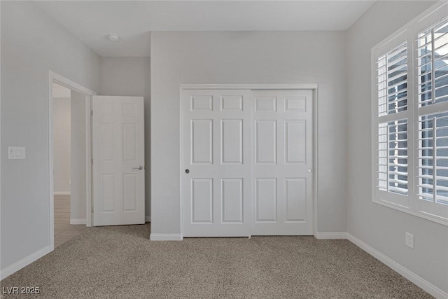 unfurnished bedroom featuring light colored carpet and a closet