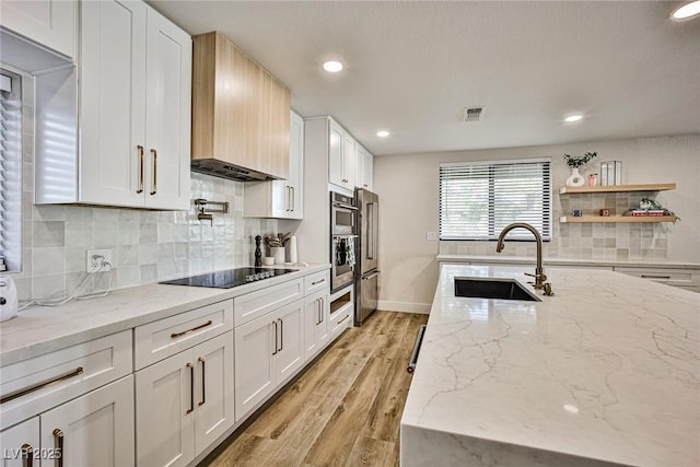 kitchen with light stone countertops, white cabinetry, sink, and appliances with stainless steel finishes