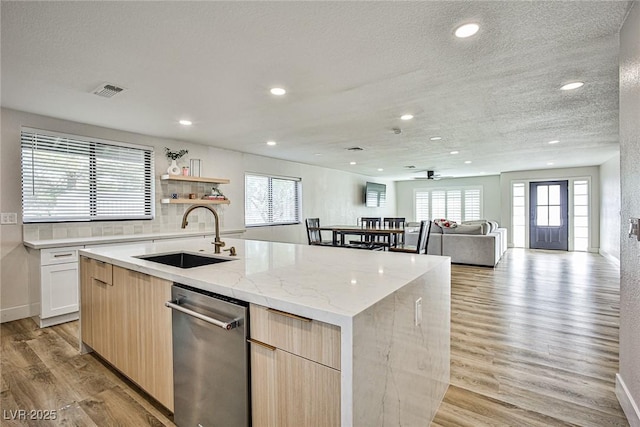 kitchen featuring backsplash, ceiling fan, a kitchen island with sink, sink, and light hardwood / wood-style floors