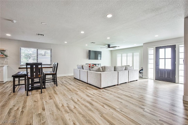 living room with a textured ceiling, light hardwood / wood-style floors, and plenty of natural light