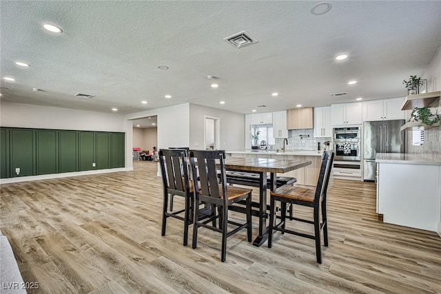 dining room with a textured ceiling, light wood-type flooring, and sink