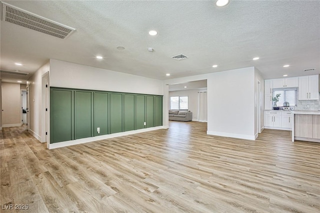 unfurnished living room with light wood-type flooring and a textured ceiling