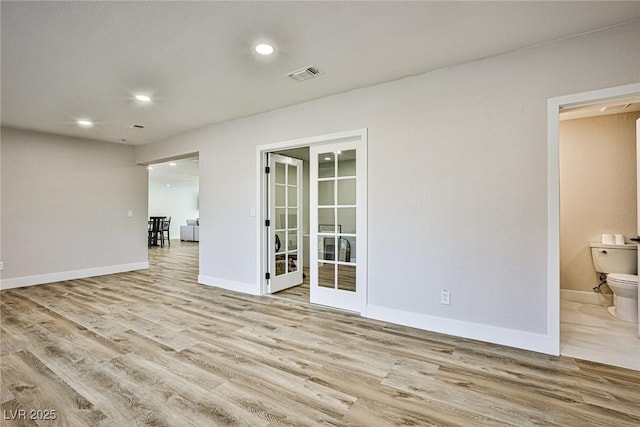 unfurnished room featuring french doors and light hardwood / wood-style flooring