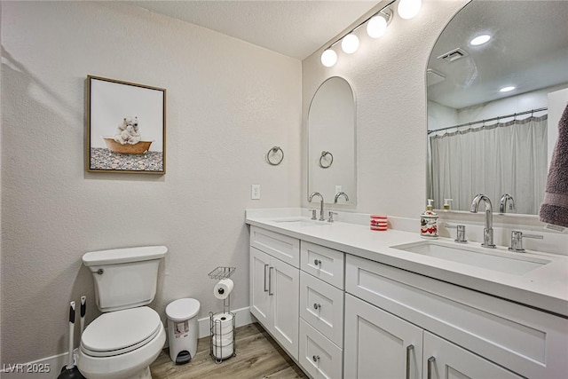 bathroom with a shower with curtain, wood-type flooring, a textured ceiling, toilet, and vanity