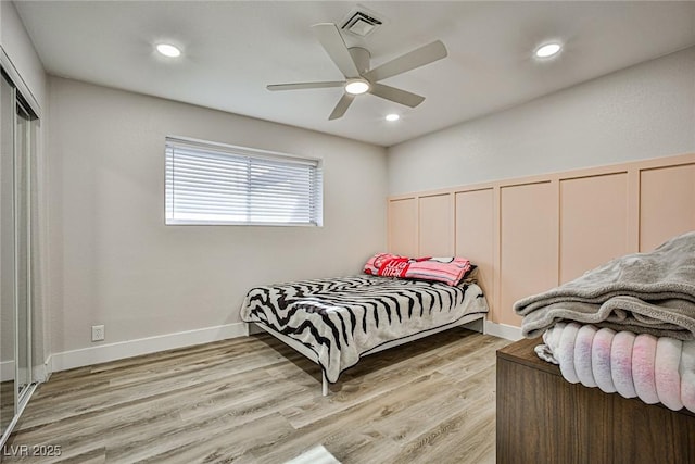 bedroom with ceiling fan, light hardwood / wood-style floors, and two closets