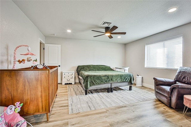 bedroom featuring ceiling fan, light hardwood / wood-style floors, and a textured ceiling