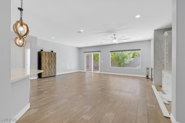 unfurnished living room featuring ceiling fan and light wood-type flooring