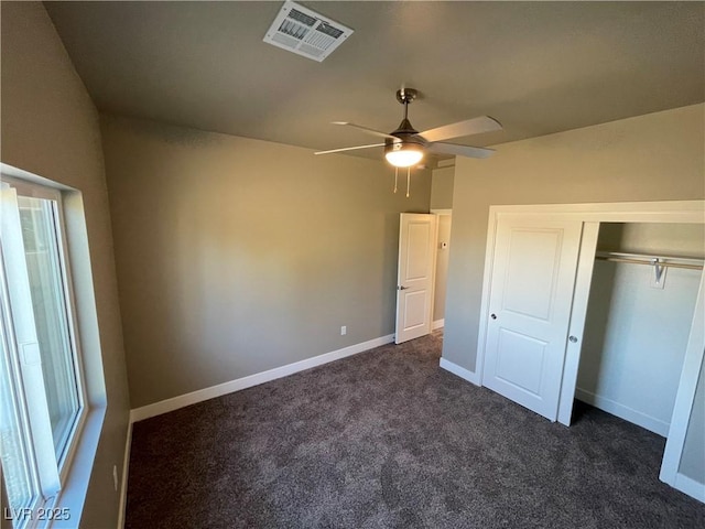 unfurnished bedroom featuring dark colored carpet, ceiling fan, and a closet