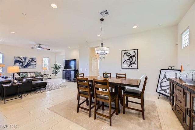 dining space featuring ceiling fan with notable chandelier, a wealth of natural light, and light hardwood / wood-style flooring