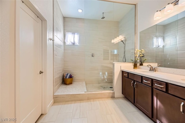 bathroom with a tile shower, tile patterned floors, and vanity