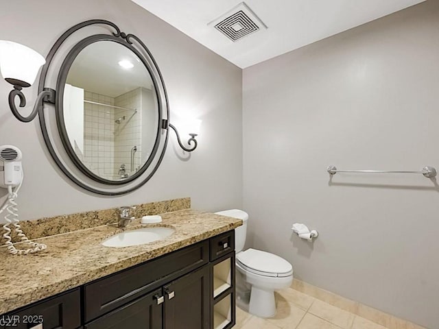 bathroom featuring tile patterned flooring, vanity, toilet, and tiled shower