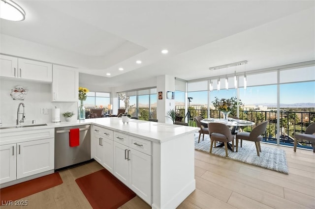 kitchen featuring kitchen peninsula, white cabinets, stainless steel dishwasher, and sink