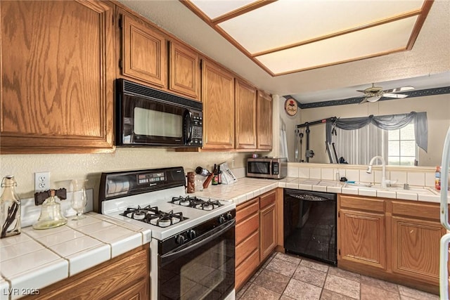 kitchen featuring black appliances, tile counters, ceiling fan, and sink