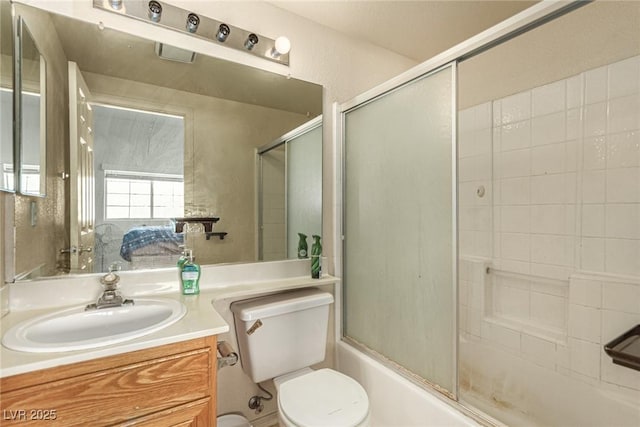 full bathroom featuring vanity, bath / shower combo with glass door, and toilet