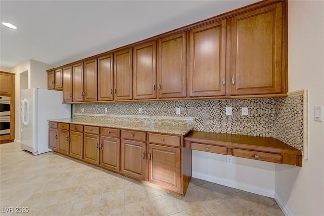 kitchen featuring white refrigerator with ice dispenser, light stone countertops, light tile patterned floors, decorative backsplash, and double oven