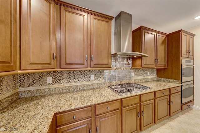 kitchen featuring stainless steel appliances, light tile patterned floors, light stone counters, wall chimney range hood, and tasteful backsplash