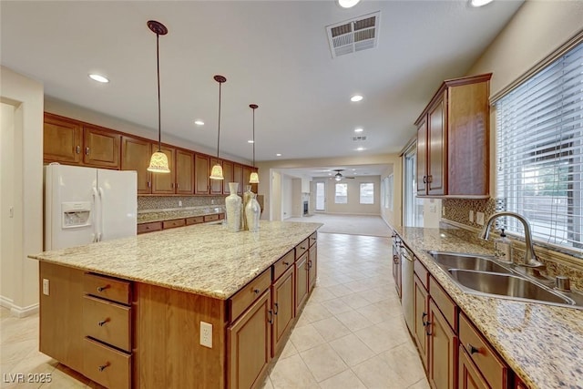 kitchen with sink, ceiling fan, hanging light fixtures, a kitchen island, and white fridge with ice dispenser