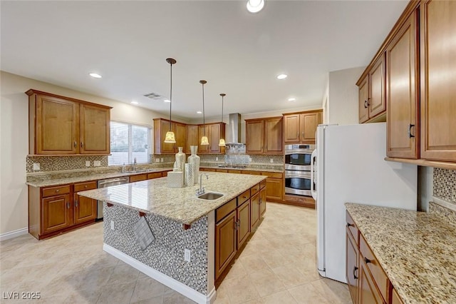 kitchen with sink, stainless steel appliances, wall chimney range hood, and decorative light fixtures