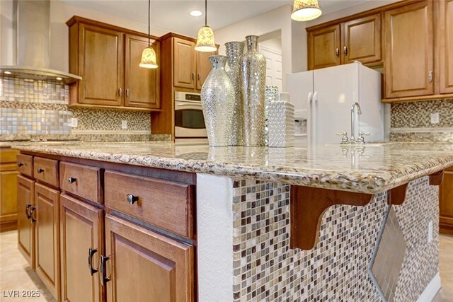 kitchen featuring white fridge with ice dispenser, pendant lighting, decorative backsplash, wall chimney exhaust hood, and oven