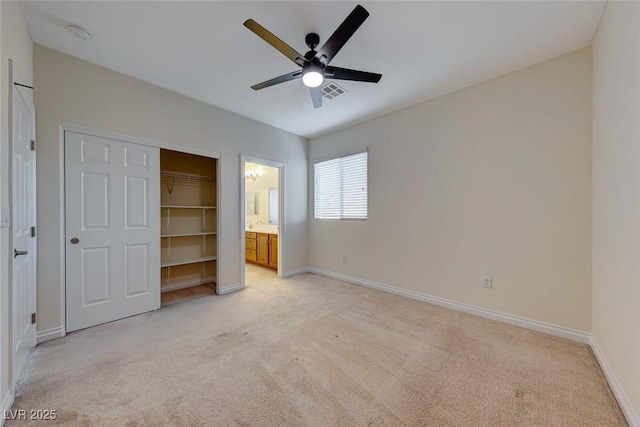 unfurnished bedroom featuring ceiling fan, connected bathroom, a closet, and light carpet