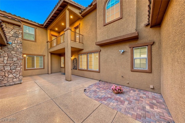 rear view of property featuring a balcony and a patio area