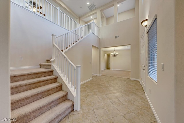 tiled foyer entrance featuring a high ceiling and a notable chandelier