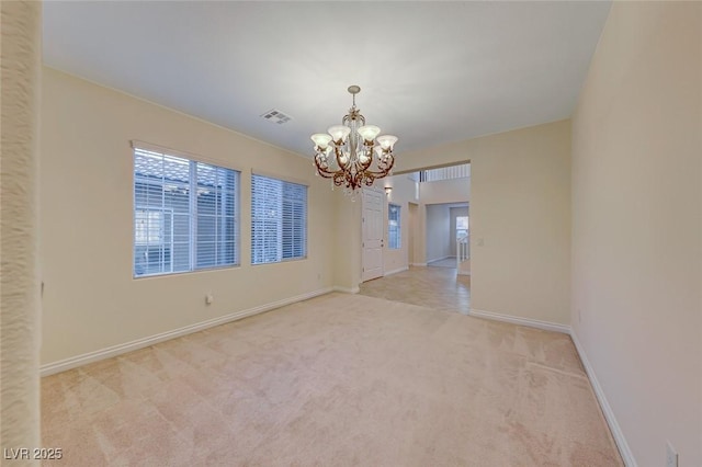 carpeted empty room featuring an inviting chandelier