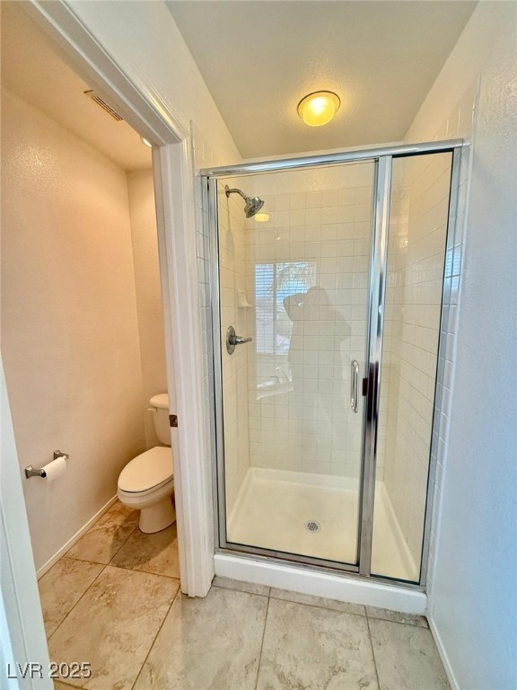 bathroom with toilet and a shower with door