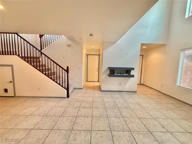 unfurnished living room with light tile patterned flooring and a towering ceiling