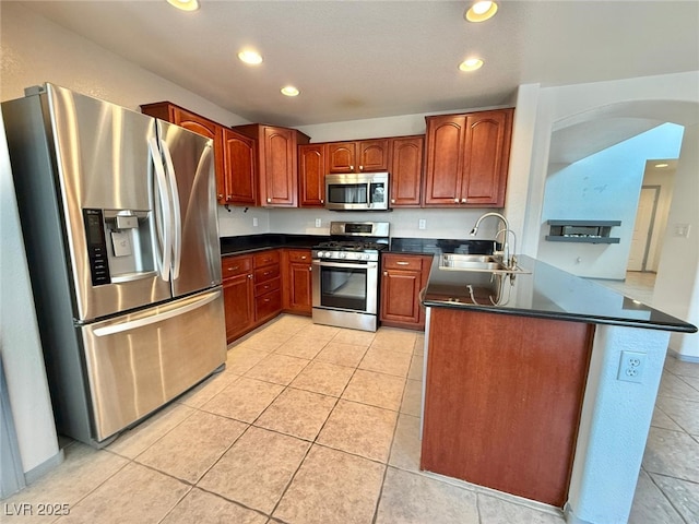 kitchen featuring kitchen peninsula, sink, light tile patterned flooring, and appliances with stainless steel finishes