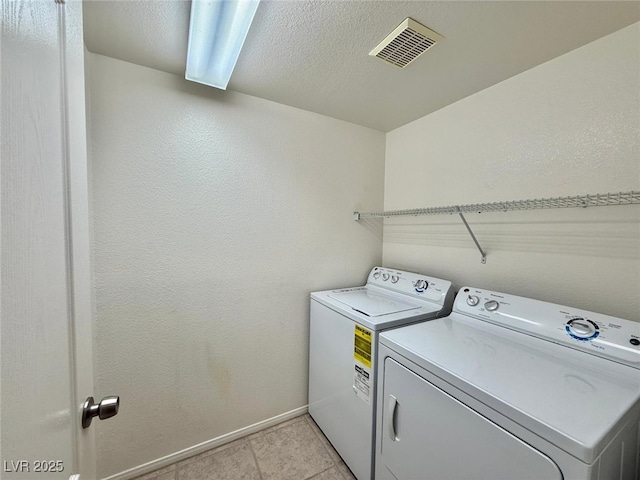 laundry area with separate washer and dryer and light tile patterned floors