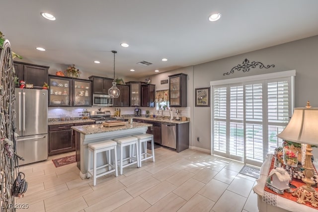 kitchen with dark brown cabinetry, appliances with stainless steel finishes, a center island, and hanging light fixtures