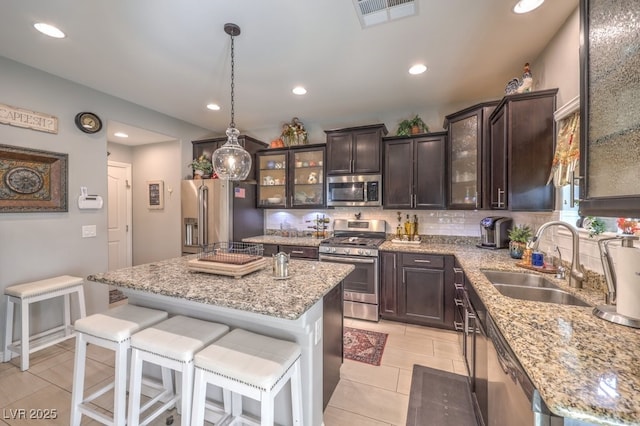 kitchen with sink, hanging light fixtures, dark brown cabinets, stainless steel appliances, and a center island