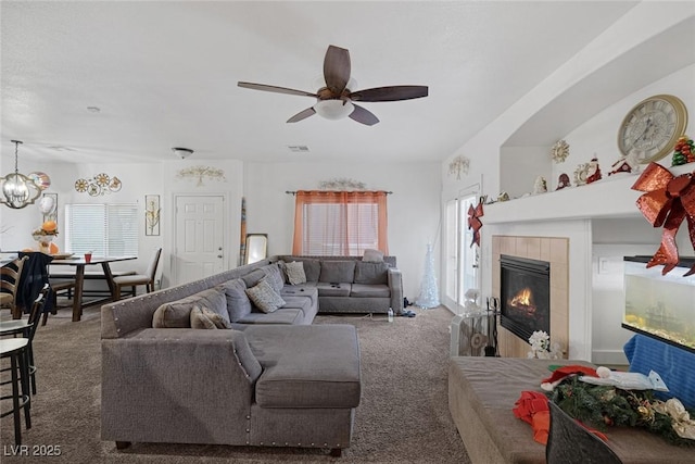 living room with dark colored carpet, ceiling fan, and a tiled fireplace