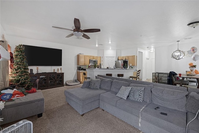 living room featuring ceiling fan with notable chandelier and light colored carpet